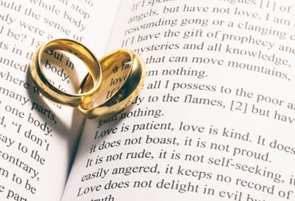 two gold wedding rings placed upon open Bible pages